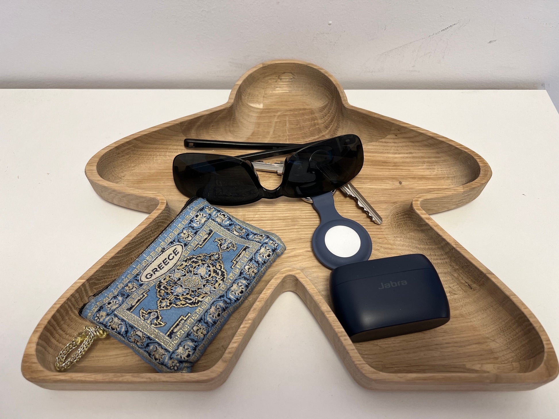 Big Meeple shaped tray containing shades, keys, a wallet and Jabra in-ear headphones